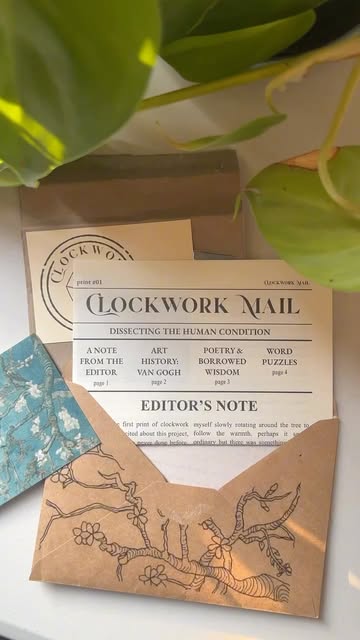 Clockwork Mail newspaper and illustrated envelope with an art print, beneath green leaves